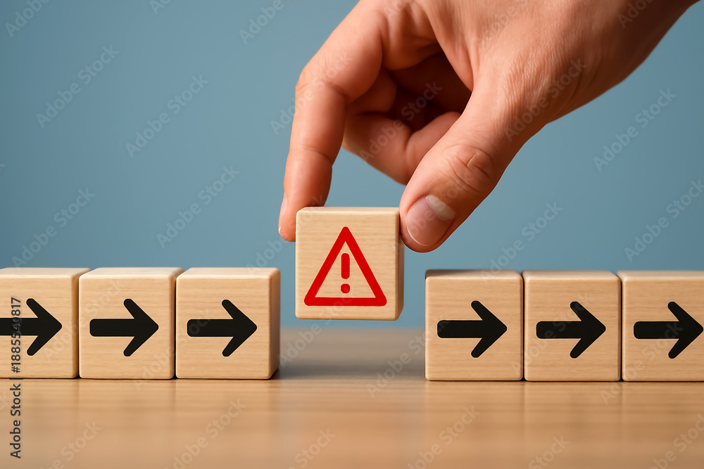 Naklejka premium Workflow disruption concept with wooden blocks showing directional arrows and red warning symbol placed by hand, symbolizing process interruption, risk alert, obstacle detection, and business problem.
