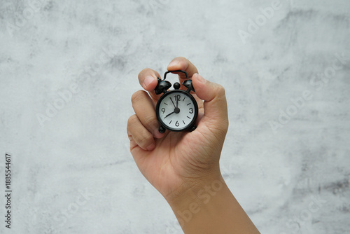 Wallpaper Mural Hand holding a small alarm clock symbolizing time management and urgency. Torontodigital.ca