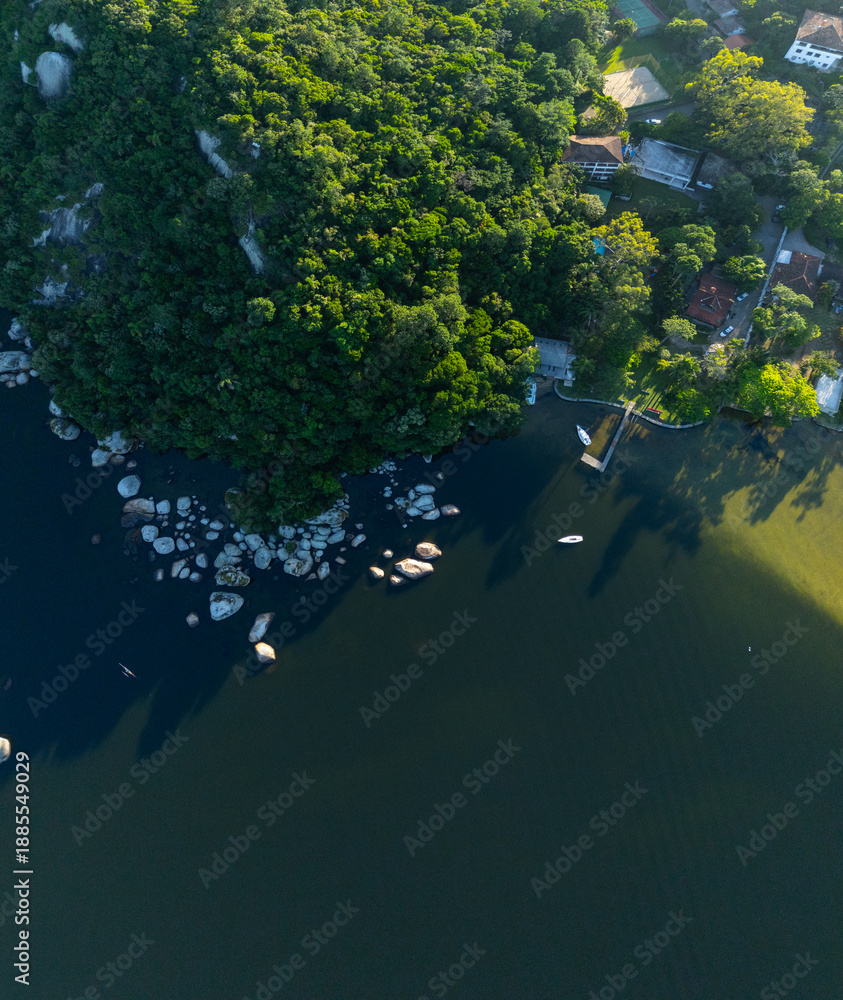 Fototapeta premium Aerial panorama of the green lush coast of the lake with buildings on the shore