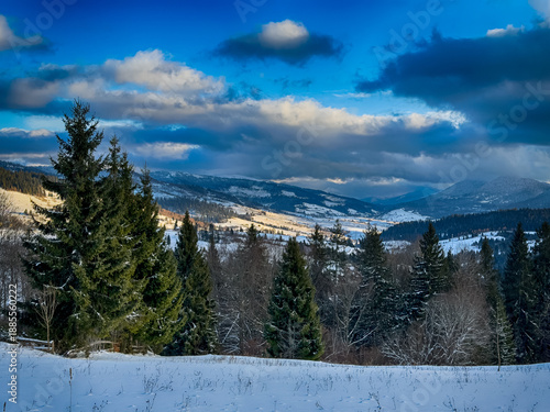 Mystical snowy Carpathian peaks under cloudy skies in the sunny weather