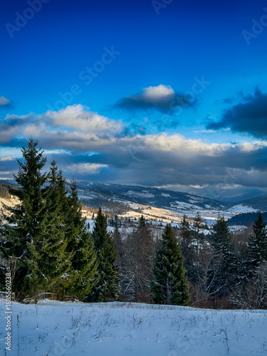 Mystical snowy Carpathian peaks under cloudy skies in the sunny weather