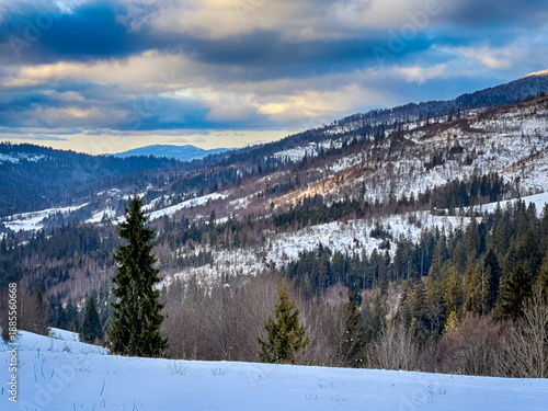 Mystical snowy Carpathian peaks under cloudy skies in the sunny weather