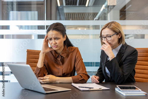 Canvas-taulu Two diverse business women in a modern office meeting room experiencing stress a