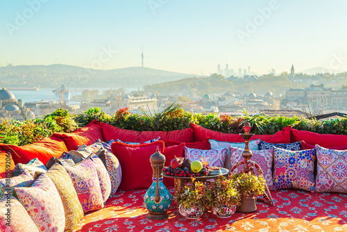 Photography Istanbul rooftop with traditional colorful Turkish carpet, pillows, hookah and fruit table