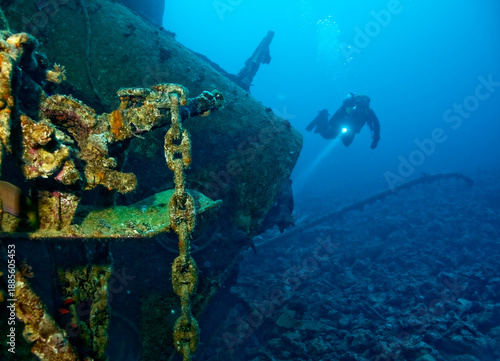 A diver with a flashlight explores a shipwreck.
