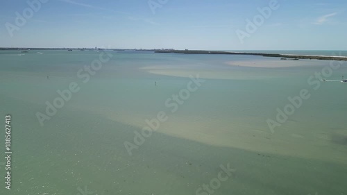 Shallow waters off the Atlantic gulf coast of Tampa Bay. As the drone flies forward you can see the sand through the water and islands just off shore. A boat also moves through the frame. 4k, drone