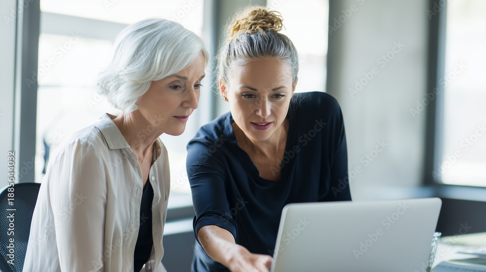 Fototapeta premium a senior mentor coaching a junior colleague while reviewing work on a laptop in office, supportive mentoring vibe, focused attentive expressions