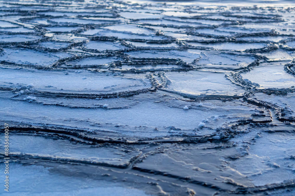 Fototapeta premium Frozen lake surface with cracked ice patterns