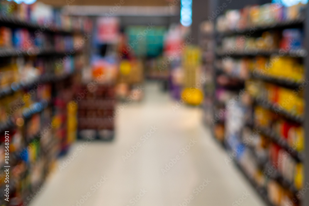 Fototapeta premium Blurry supermarket aisle with colorful products on shelves
