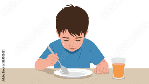 Sad young boy sitting at a table with a spoon and an empty white plate looking disappointed because he is hungry or dislikes the food provided.