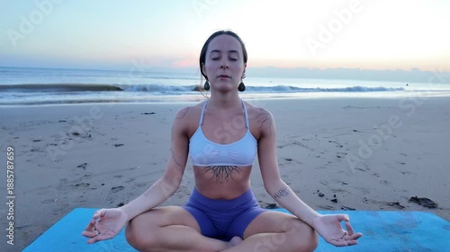 Lesbian woman meditating on a beach at sunrise