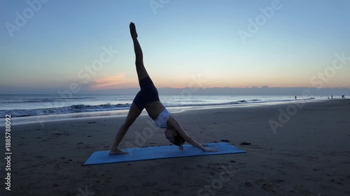 Lesbian woman performing advanced yoga poses on the beach at sunrise