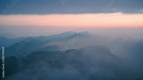 Panoramic view of the Alishan mountain range at sunset, featuring a breathtaking sea of clouds rolling over the peaks. The sky displays soft pink and blue hues. Shizhao, Taiwan.