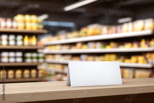 Wallpaper Mural Blank Sign in Grocery Store: A simple, blank sign stands prominently on a wooden table in a well-stocked grocery store, inviting potential customization and information display. Torontodigital.ca