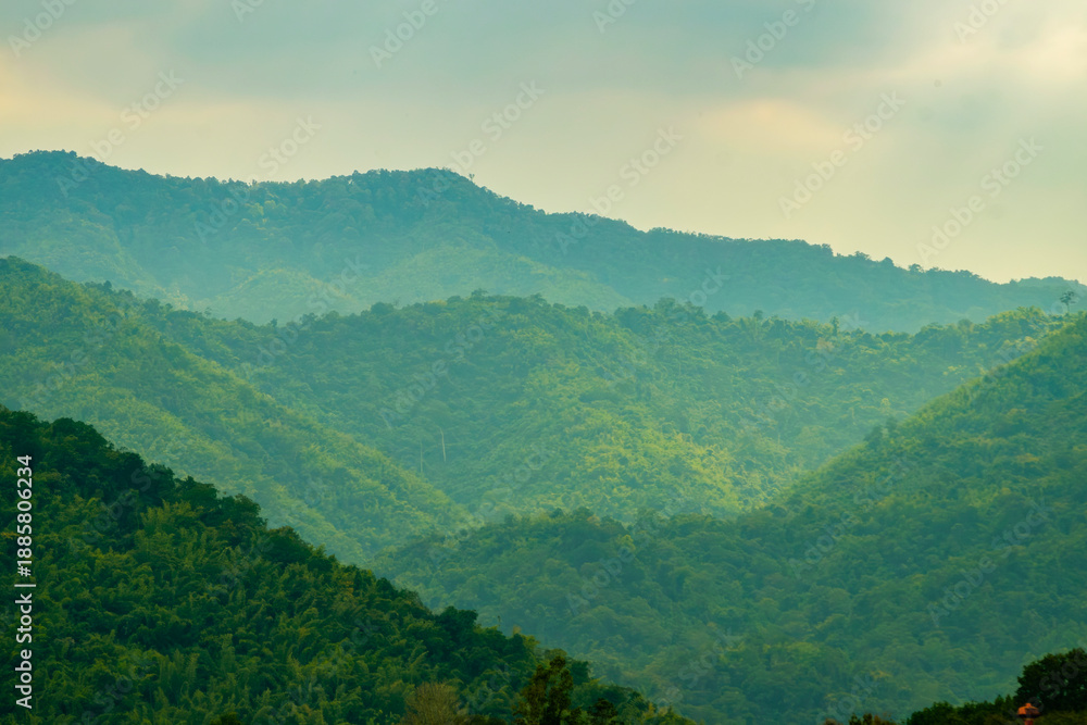 Naklejka premium Layers of Green Mountains in Soft Light Symbolizing Calm and Renewal