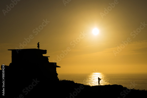 Tourist watching warm summer sunset over ocean coastline in Galicia, Spain