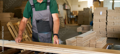 A worker in a woodworking plant uses a planer to produce parquet boards.