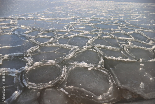 Close-up of forming ice floes on the Baltic Sea. Delicate ice textures and patterns emerge on the water surface, creating a crisp, very graphic and minimalist composition. No people present, with ampl