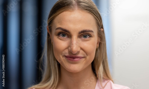 Woman facing camera maintaining eye contact in studio wearing pink blouse gold-hoop on left ear