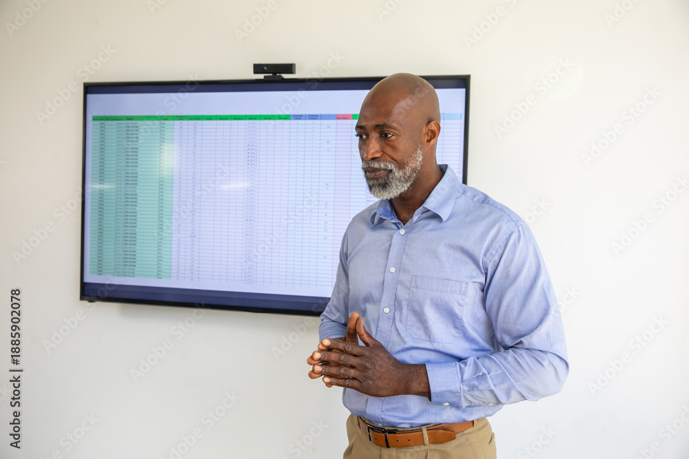 Obraz premium Senior African American man in shirt showing spreadsheet with webcam in meeting room, copy space