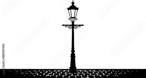 Silhouette of a vintage street lamp on a cobblestone road