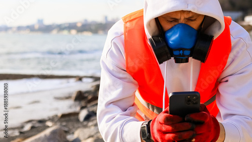 Billede på lærred Man in respirator using smartphone on rocky shore