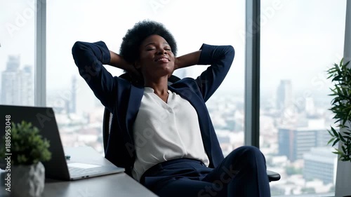 Woman in suit resting at office desk looking out window