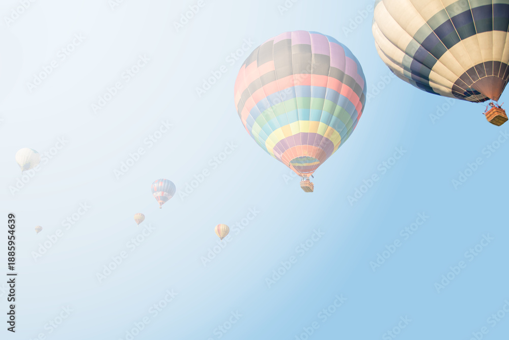 Obraz premium Vibrant Hot Air Balloons Soaring Through a Misty Blue Sky at Dawn
