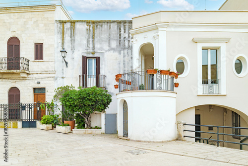 Bari, Italy. Facade of historic buildings and homes along Via Venezia in Bari, featuring light stone walls, balconies with plants and elegant details in a quiet pedestrian area.