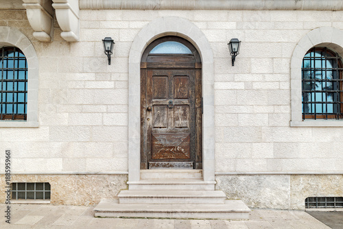 Bari, Italy. Historic stone facade along Via Venezia in Bari, featuring an arched wooden door, iron grilles and wall lamps, expressing the timeless character of the old city.