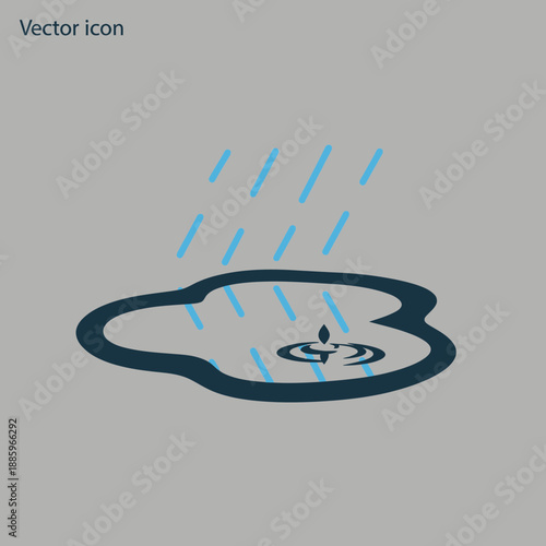 Rain falls into a puddle creating ripples in the water.