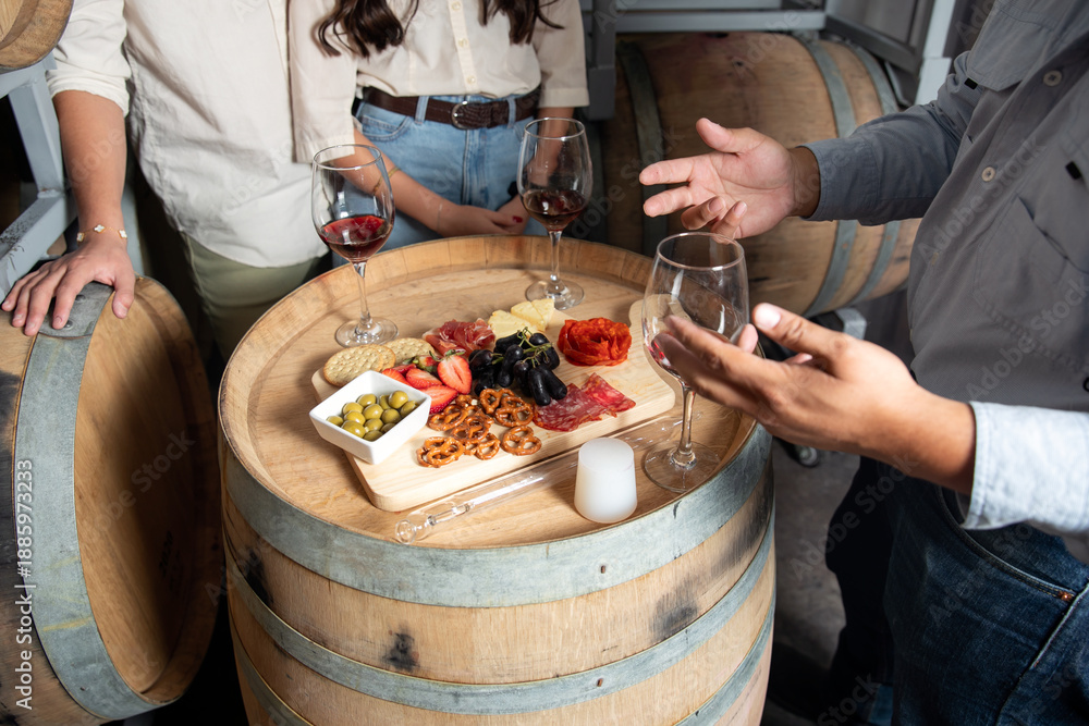 Fototapeta premium Wine tasting experience with charcuterie board on barrels in a cellar