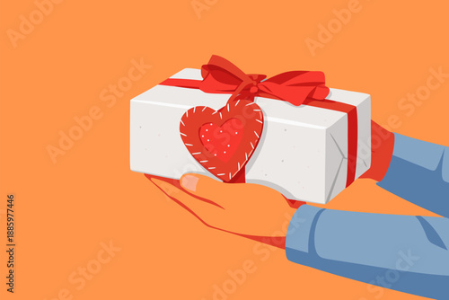 A close up view shows hands holding a gift box with a red heart.
