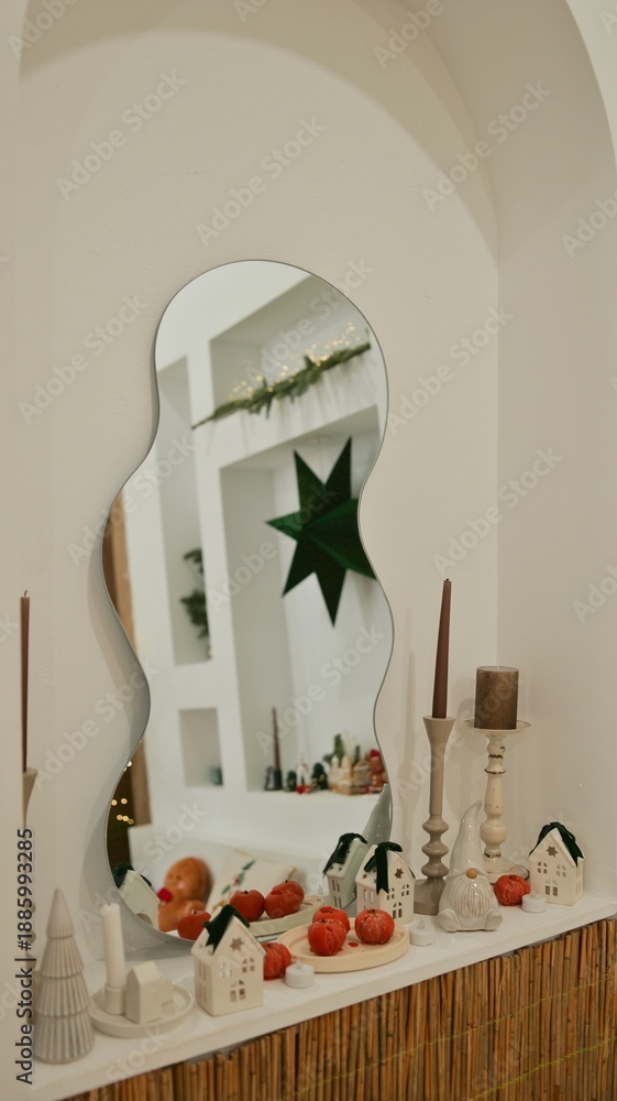 Fototapeta premium Cozy Christmas mantelpiece with decorative houses, pumpkins, and a star in the mirror reflection