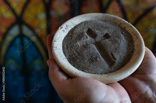 Bild auf Leinwand Hands with gray ash cross in church on stained glass window
