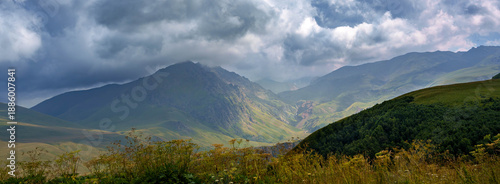 Open mountain landscape with grassy hills and cloudy blue sky. Natural background with no people