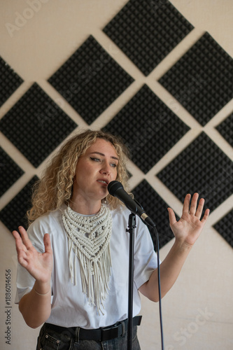 Photography Caucasian woman singing into microphone in music studio.