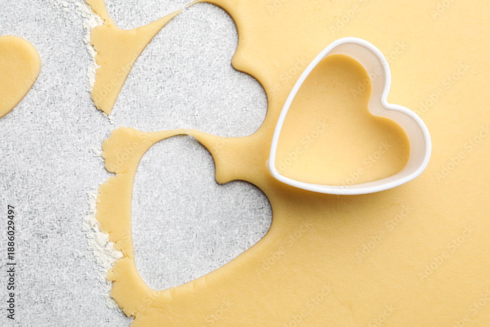 Obraz premium Uncooked heart shaped cookies and raw dough on light gray table, top view