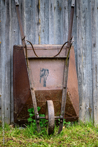 rusty wheelbarrow by the boards on a green grass day