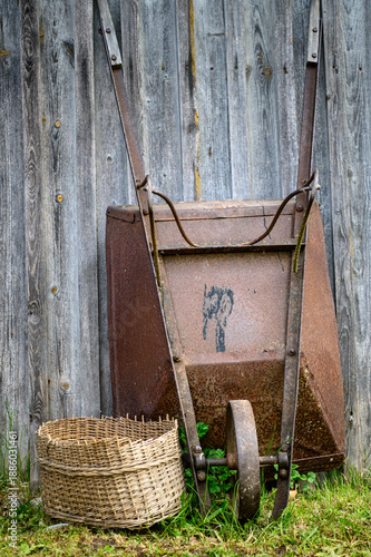 rusty wheelbarrow by the boards on a green grass day