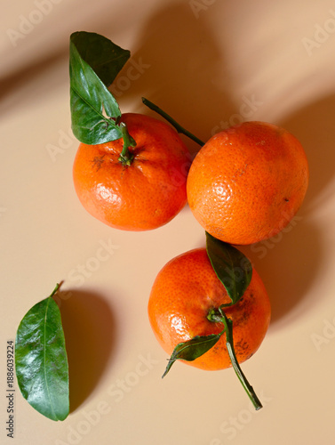 Fresh mandarins with green leaves on warm background symbolizing festive atmosphere, winter holidays, natural aroma, coziness and joyful seasonal mood