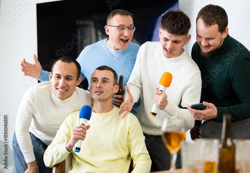 Fotografía Cheerful male friends having fun while singing karaoke at a bar