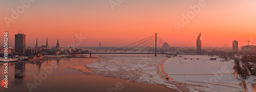 Fotografie Riga, Latvia at winter sunset shows Vansu Bridge, Old Town spires, the Riga Radio and TV Tower, and a Z Towers style high rise by the partly frozen Daugava River