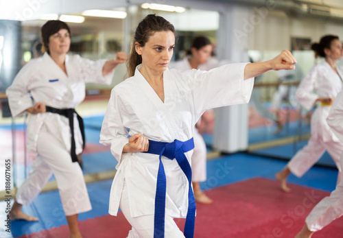 Fotografija Group of women in kimonos train karate techniques in studio