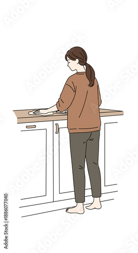 Woman cleaning kitchen countertop while standing barefoot indoors  