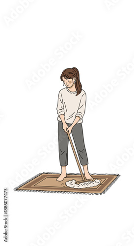 Young woman cleaning a rug with a broom at home  