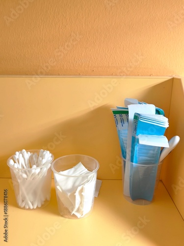 Cotton swabs, wipes and spatulas in plastic cups on a shelf