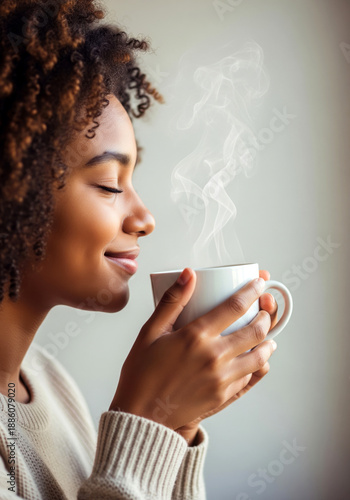 Smiling African American girl smelling aroma of fresh hot coffee with eyes closed on white background