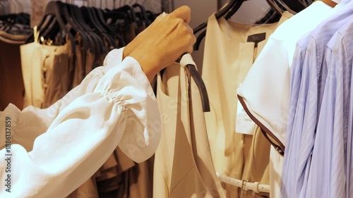 Browsing fashion store customer selects modern stylish outfit Stylish woman explores clothing store racks compares looks enjoys shopping mood Trendy pieces found inside store for wardrobe update