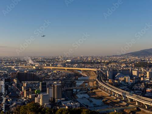 朝日に照らされた都市と青空を飛ぶ飛行機